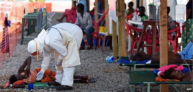 A nurse wearing personal protective equipment (PPE) checks on a patient at the Kenema Ebola treatment centre run by the Red Cross on November 15, 2014