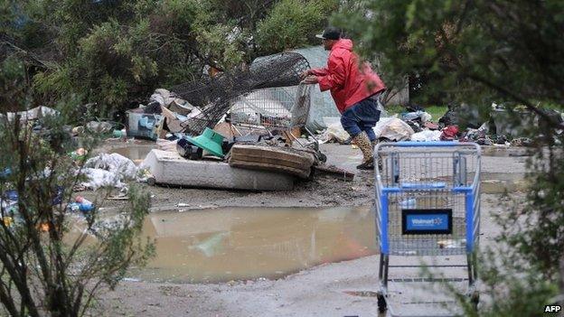 An man pushes a trolley in a homeless encampment known as "the Jungle"