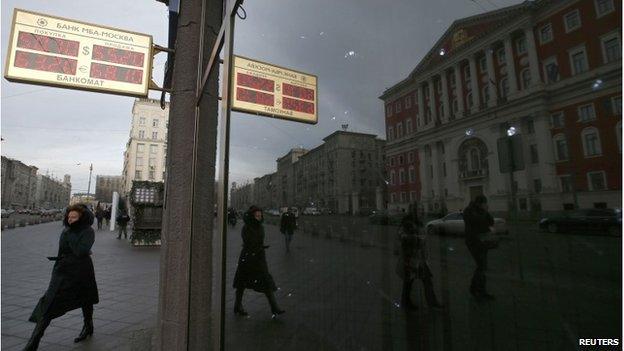 Woman walks past sign showing currency rates in Moscow, 3 December 2014