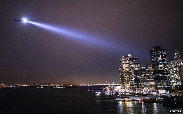 A police helicopter shines a search light towards marchers near the Brooklyn Bridge, New York, 4 December