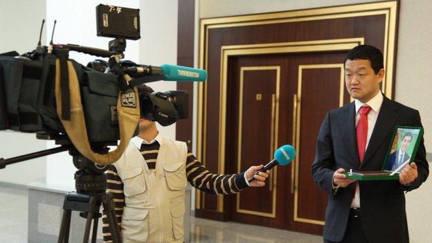 Conference delegate holds portrait of Turkmen president for TV cameras (Nov 2014)