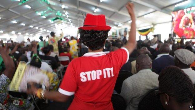 A supporter of Zimbabwean President Robert Mugabe chants the party's slogan while wearing a t-shirt urging people to stop plotting to remove the president from power, in Harare, 6 December 2014