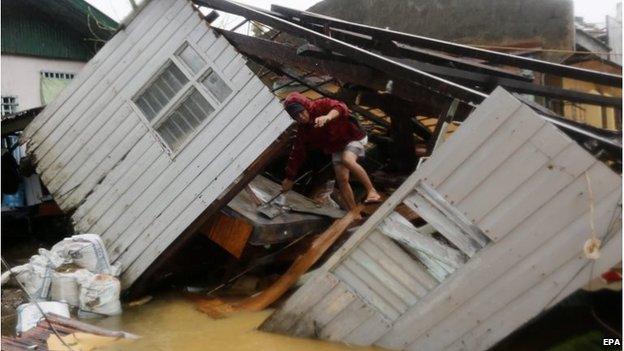 Man climbs over fallen building in Borongan city, Samar island (7 Dec 2014)