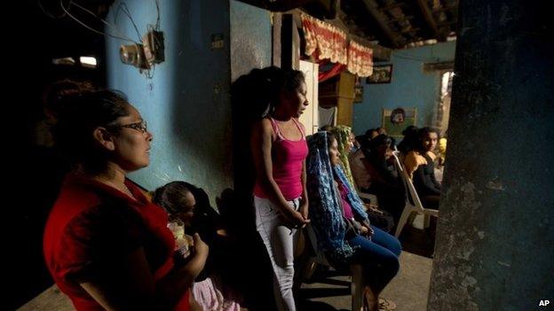 Women pray in front of an altar to the memory of Alexander Mora on 7 December 2014