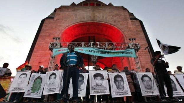 Felipe de la Cruz, the father of one of the 43 missing students, speaks to a crowd in front of other relatives holding posters of their missing loved ones, during a protest at the Revolution Monument in Mexico City on 6 December, 2014