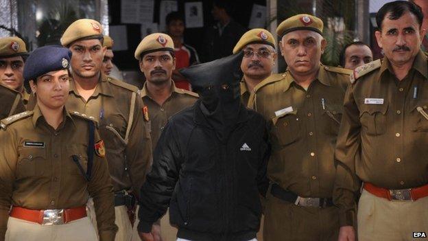 Police personnel escort taxi driver (wearing mask), accused of raping a female finance company executive, as he is taken to court in New Delhi, 08 December 2014.