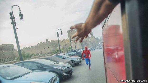 A man dressed as Spider-Man runs for a bus