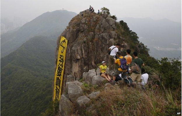 Hikers take pictures of the yellow banner with the words reading: "I want genuine universal suffrage" in Chinese and "Umbrella Movement" in English hanging from the face of Lion Rock mountain in Hong Kong Thursday, 23 October 2014