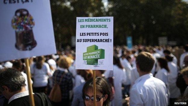 A pharmacist holds a placard reading "Drugs in pharmacies, peas at the supermarket. Your pharmacy is threatened" in a 30 Sept 2014 protest in Nantes