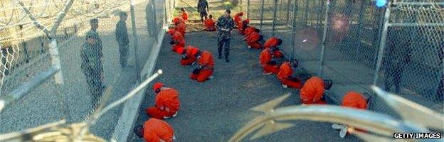 U.S. Military Police guard Taliban and al Qaeda detainees in orange jumpsuits January 11, 2002