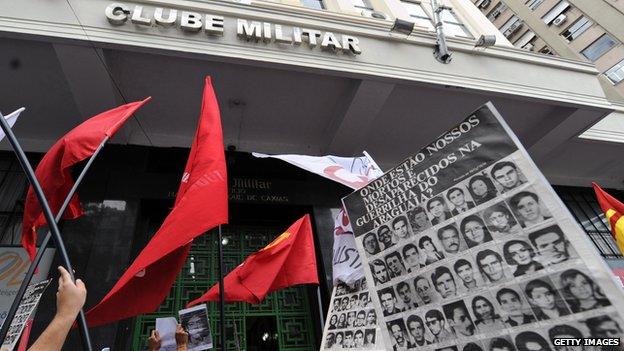 Relatives of tortured and disappeared people hold a banner with pictures of the victims in Rio de Janeiro on 29 March, 2012.