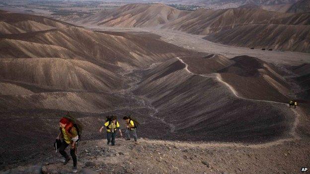 Greenpeace activists walk towards the historic landmark of the hummingbird in Nazca on 8 December, 2014.