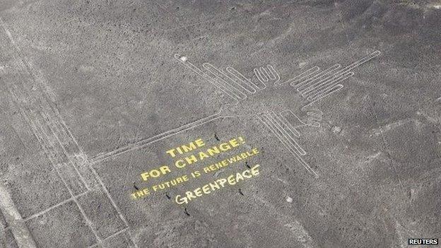 Greenpeace activists stand next to massive letters delivering the message "Time for Change: The Future is Renewable," next to the hummingbird geoglyph in Nazca on 8 December, 2014