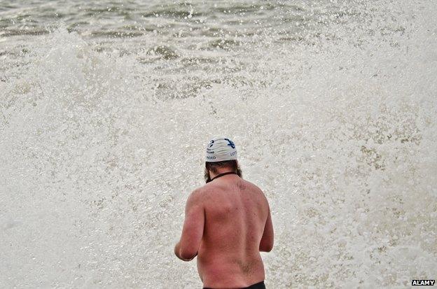 Man in swimsuit contemplates cold sea