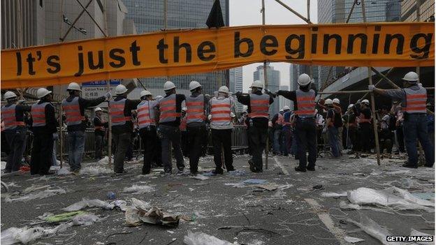 Workers remove a banner in Hong Kong (11 Dec 2014)