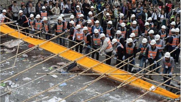 Workers remove a banner in Hong Kong (11 Dec 2014)