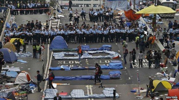 Police stand as they clear an area, previously blocked by pro-democracy, near the government headquarters building at the financial Central district in Hong Kong, 11 December 2014.