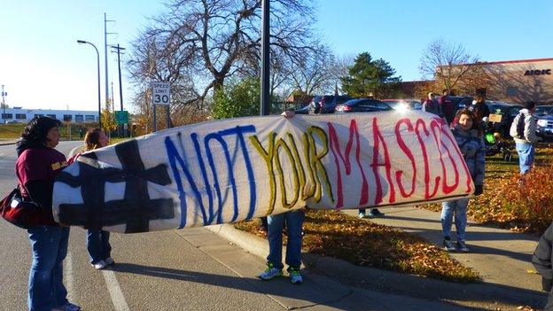 Activists fly a #notyourmascot banner at an anti-Redskins rally