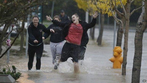 A group of girls laugh while running down a flooded street in Healdsburg, California 11 december 2014