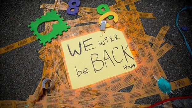 'We Will Be Back' is displayed on a sign taped to the road outside Hong Kong's Government complex on December 11, 2014 in Hong Kong