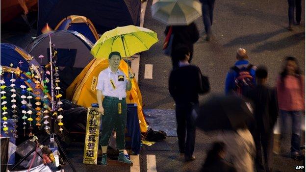 A cardboard cut-out of Chinese President Xi Jinping (C) carrying a yellow umbrella is seen at the pro-democracy movement's main protest site in the Admiralty district of Hong Kong on 2 December 2014