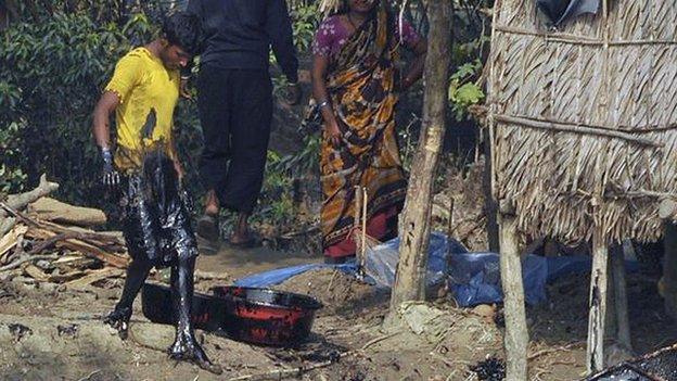 Bangladeshi villagers try to collect oil, handout photograph received from the World Conservation Society on December 12, 2014