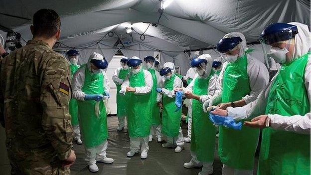 Military personnel in medical protective gear training for a deployment to Sierra Leone