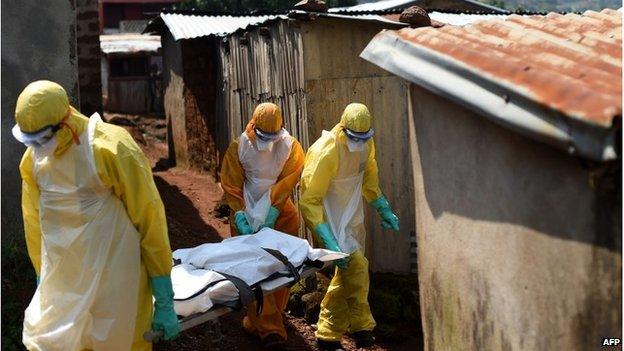 Health workers from Sierra Leone"s Red Cross Society Burial Team 7 carry a corpse out of a house in Freetown on November 12, 2014