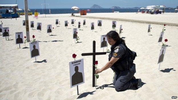 Police officer lays crosses on Copacabana beach, 9 Dec 14