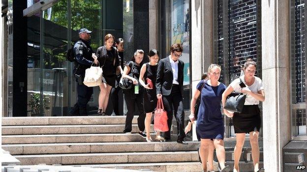 Armed police evacuate employees from the offices next to a cafe in the central business district of Sydney on 15 December 2014.