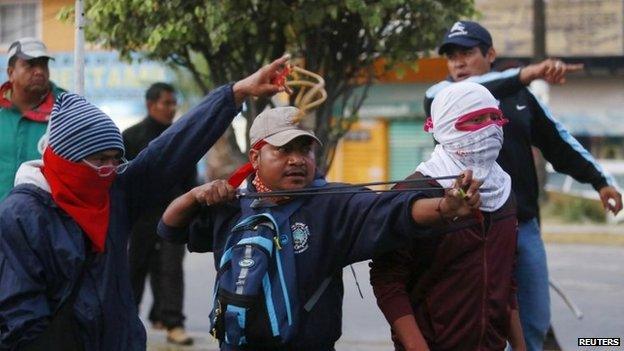 Members of a Guerrero teachers' union use slingshots to throw stones at federal police officers during clashes in Chilpancingo on 14 December, 2014