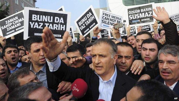 Zaman editor-in-chief Ekrem Dumanli (c) with supporters after leaving Zaman newspaper HQ in Istanbul