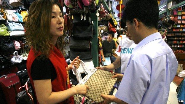 Customers look at a fake Gucci hand bag in Beijing's famous Silk Alley market.