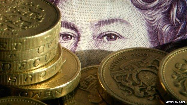 Sterling pound coins stacked in front of a twenty pound note