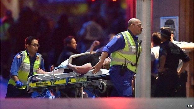 An injured hostage is carried out of a cafe in the central business district of Sydney on December 16, 2014.