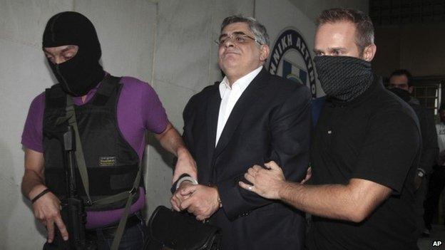 Sept. 28, 2013 file photo of leader of the extreme far-right Golden Dawn party Nikos Michaloliakos as he is escorted by anti-terror police as he exits Greek Police headquarters in Athens