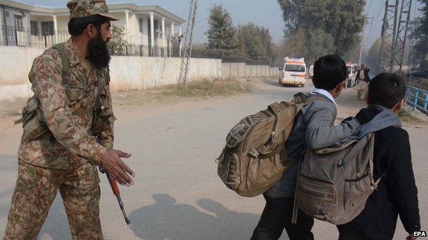 Children being ushered away from the scene of a gun attack in Peshawar