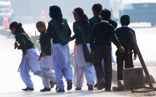 Schoolchildren cross a road as they move away from a military run school that is under attack by Taliban gunmen in Peshawar, 16 December 2014.