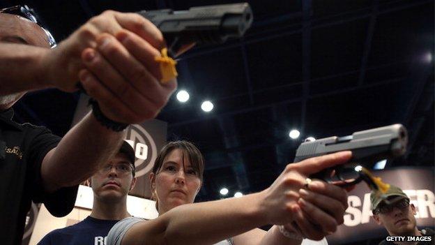 Attendees hold handguns in the Sig Sauer booth during the 2013 NRA Annual Meeting and Exhibits at the George R Brown Convention Center 4 May 2014