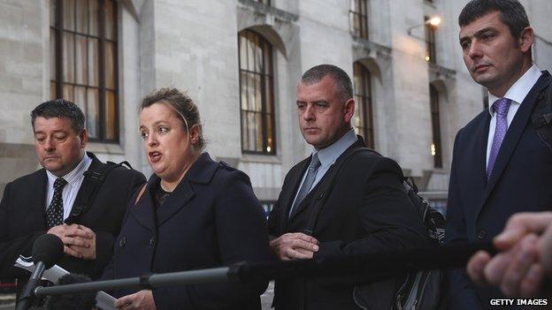 Terence Hughes (L), Colin Kaler (2ndR) and Stuart Tribelnig (R) stand as a spokeswoman speaks to members of the media