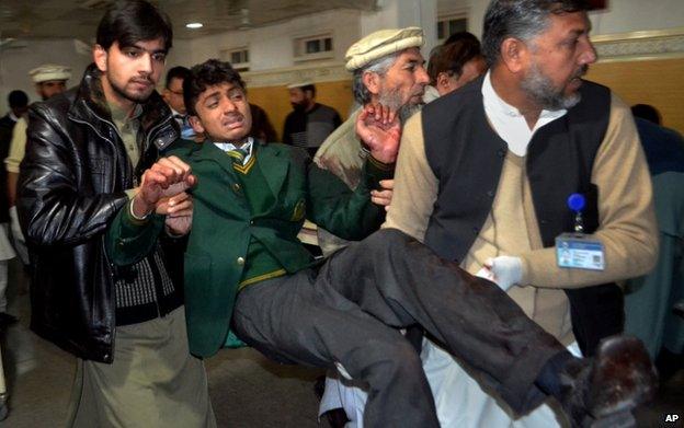 Pakistani volunteers carry a student injured in the shootout at a school under attack by Taliban gunmen, at a local hospital in Peshawar, Pakistan. 16 December 2014