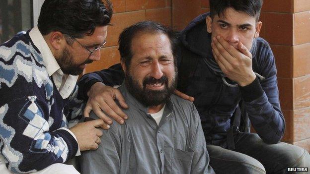 Relatives of a student, who was injured during an attack by Taliban gunmen on the Army Public School, comfort each other outside Lady Reading Hospital in Peshawar, 16 December 2014