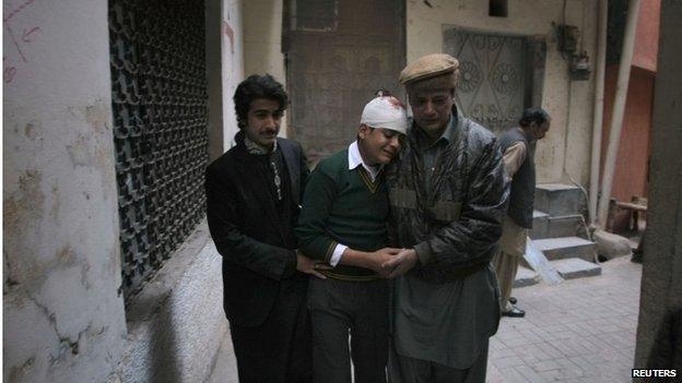 An injured student with relatives mourns the death of his mother who was a teacher at the school which was attacked by Taliban, in Peshawar, Pakistan, 16 December 2014