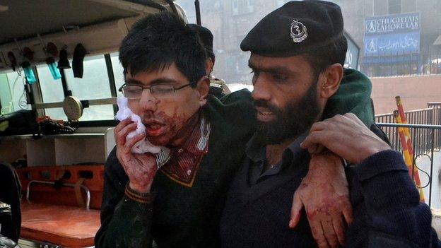 A man helps an injured student following a mass shooting in Peshawar - 16 December 2014