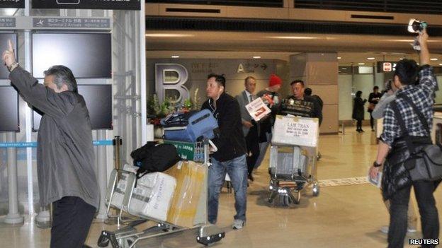 Passengers on an American Airlines flight arrive after it made an emergency landing at Narita international airport, east of Tokyo, on 17 December 2014