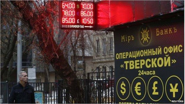 Man walking past currency exchange board