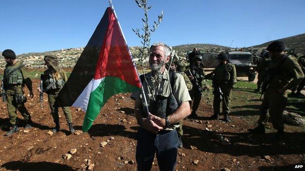 A man holds a Palestinian flag during a demonstration near Ramallah, 10 Dec 14