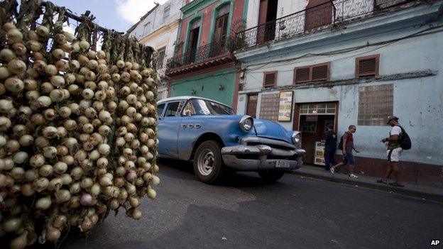 A classic American car passes by a stall selling onions in Havana, Cuba, on 17 December 2014.