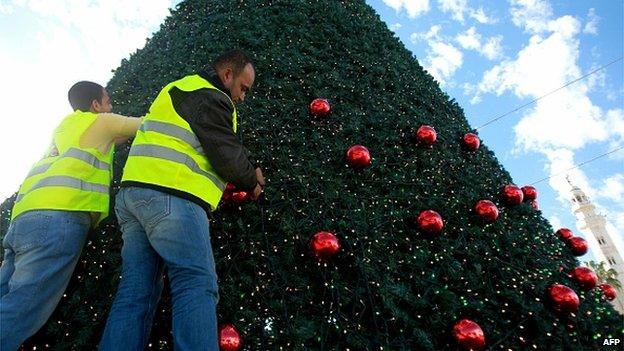 Workmen decorate a Christmas tree in Manger Square