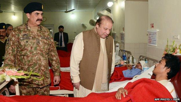 Pakistani Prime Minister Nawaz Sharif (C) talks to an injured student at the military hospital in Peshawar, as army chief General Raheel Sharif (L) looks on.